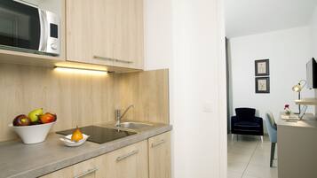 Een moderne keuken met houten kastjes, een ingebouwde magnetron, een spoelbak en een schaal fruit.