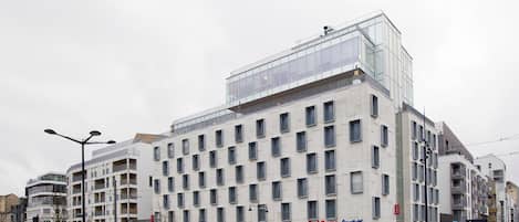 Un hotel moderno con fachada de vidrio, varios pisos y una entrada destacada.