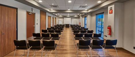 Un salón de conferencias con filas de sillas, una pizarra y un extintor.