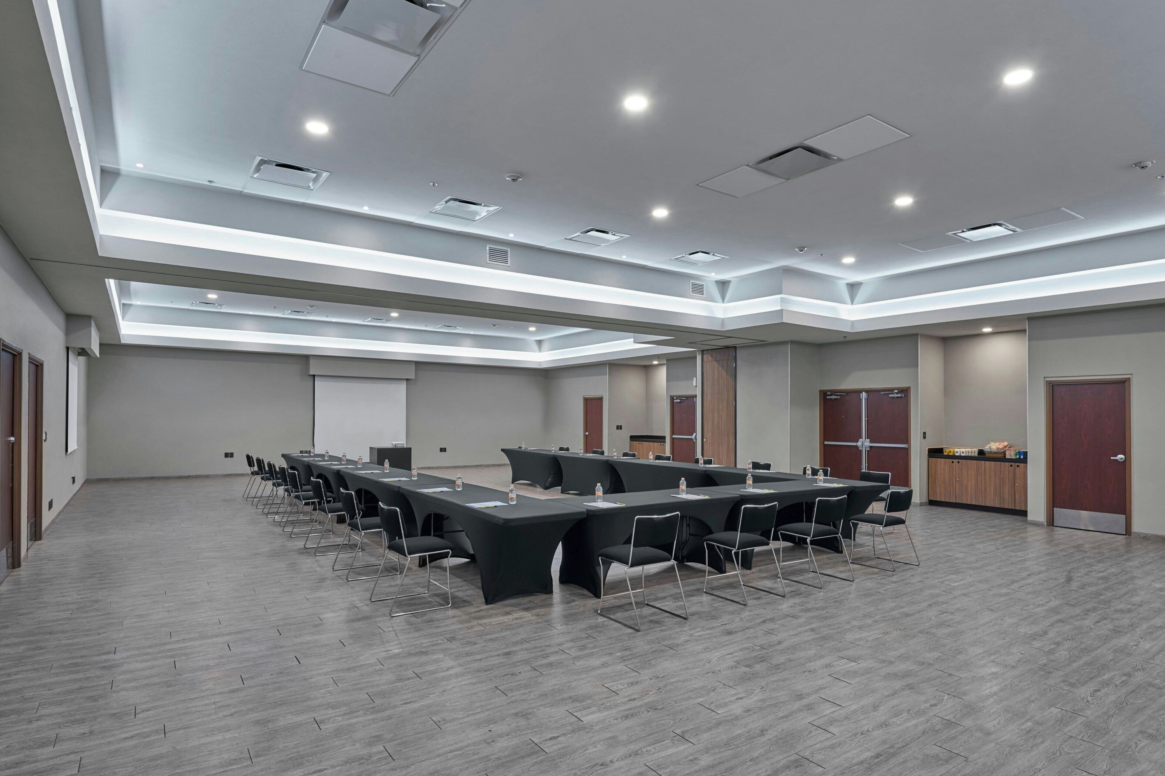 Una sala de conferencias con una mesa larga, sillas y una pantalla para proyector.