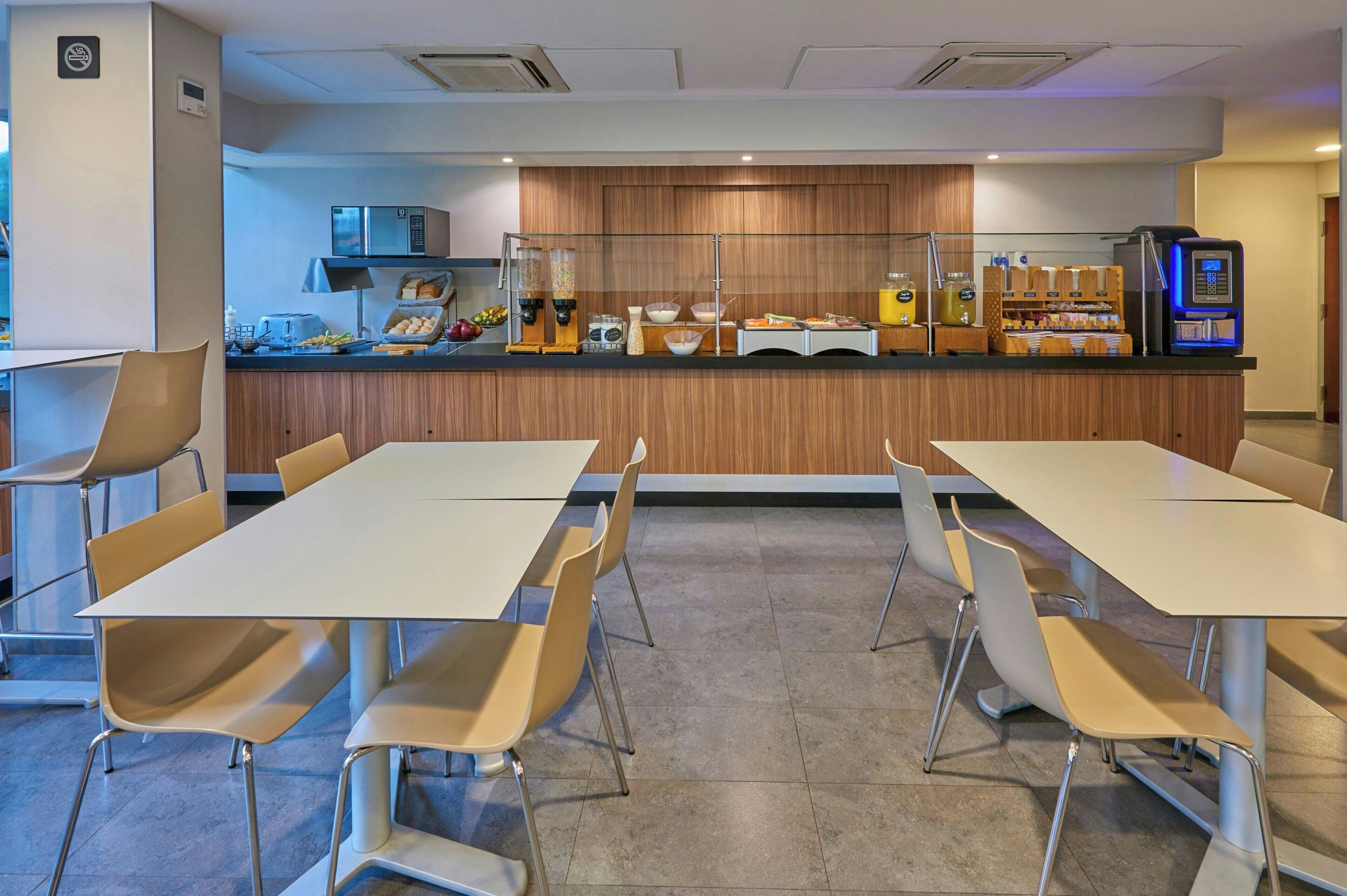 A modern breakfast area with a long counter, microwave, and coffee machine.