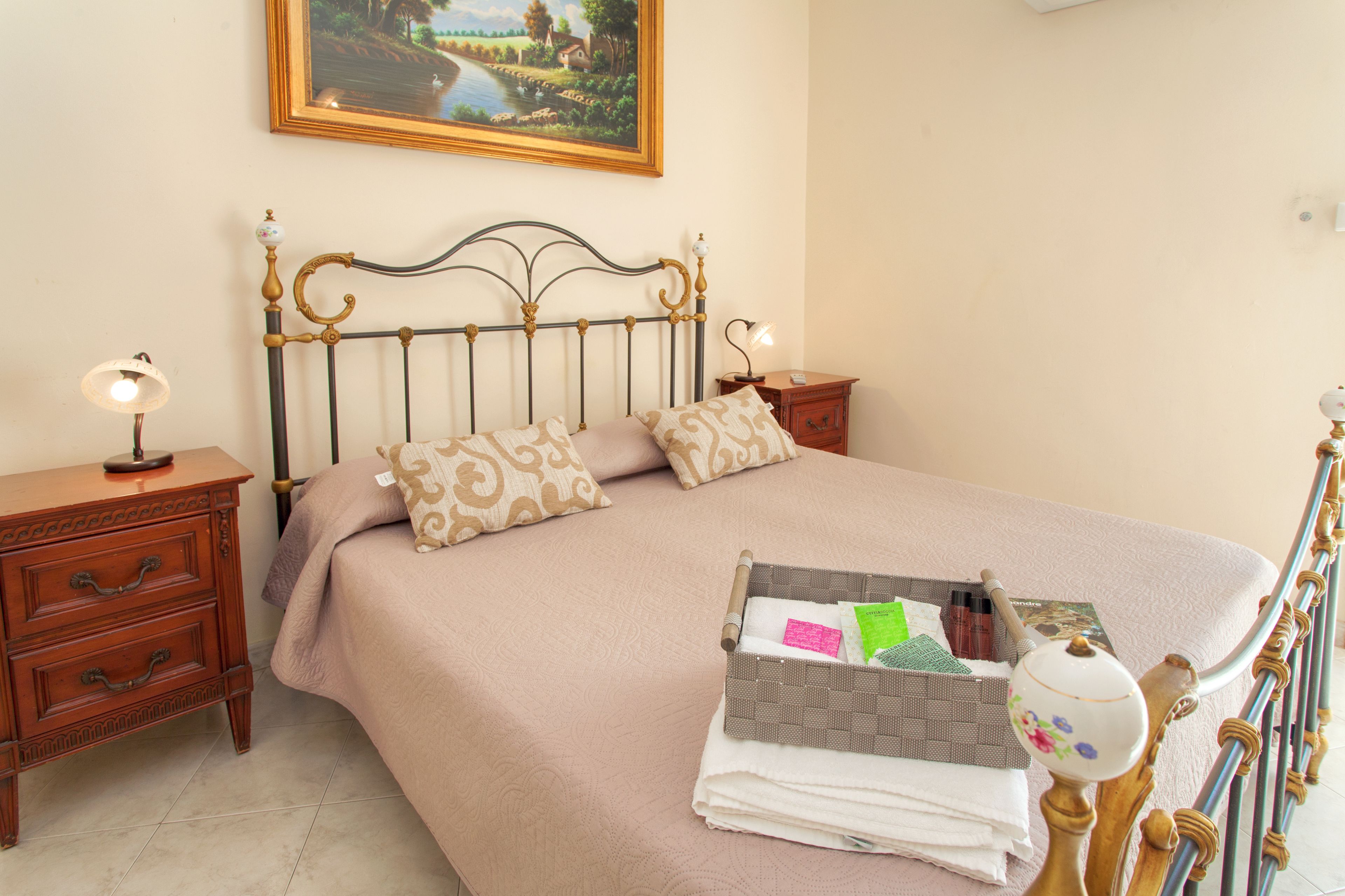 A neatly made bed with a headboard, two bedside tables with lamps, and a bedside basket.