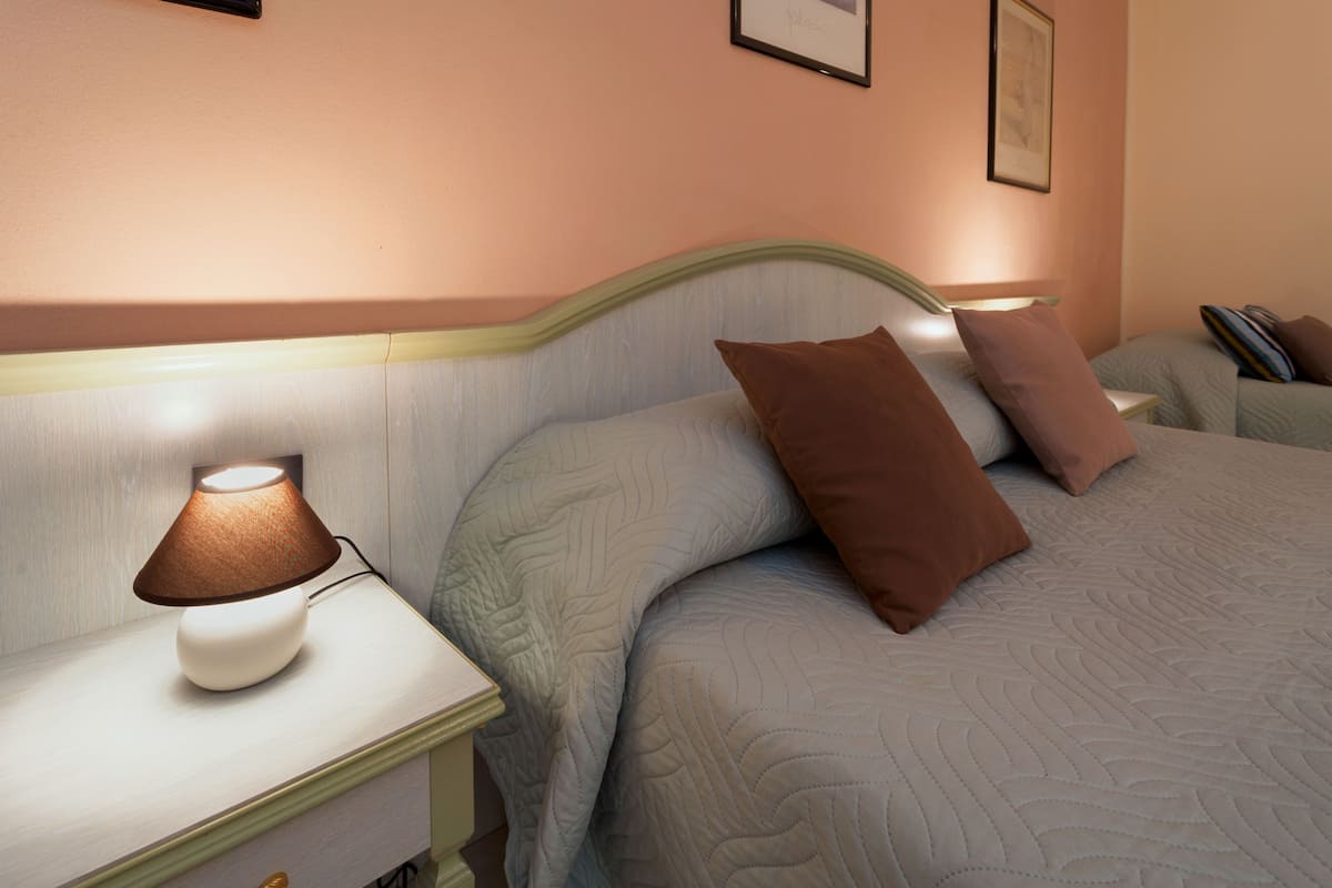 A neatly made bed with a headboard, a bedside lamp, and two pillows.