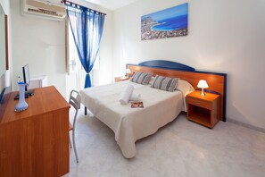 A hotel room with a bed, bedside tables, a desk with a computer, and a window with curtains. - Al Piazza Marina B&B (Palermo)