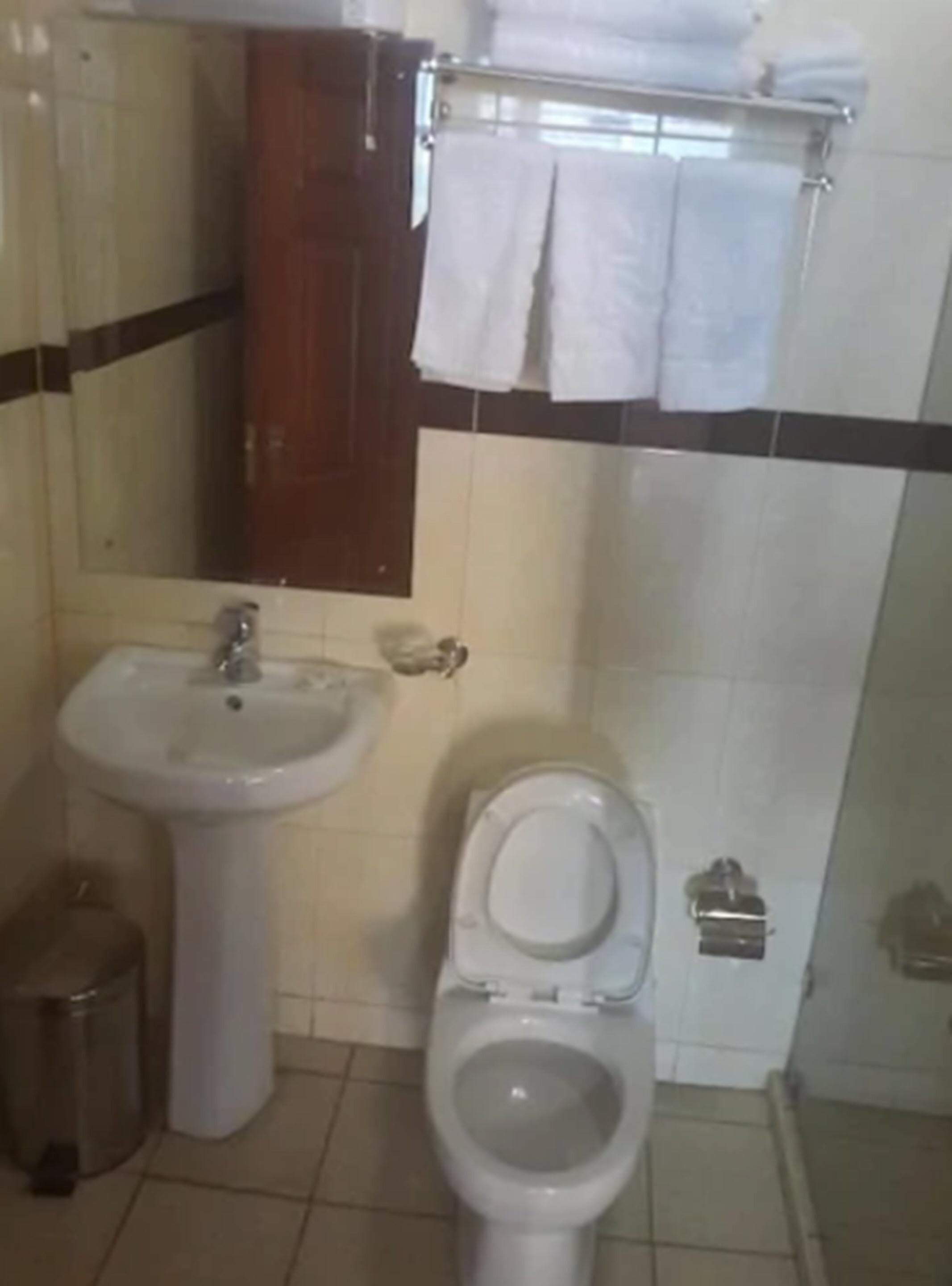 A bathroom with a sink, toilet, and a mirror.
