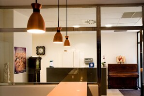 A reception area with a reception desk, a clock, and a poster on the wall. - Imprenta Musical Alojamiento (Astorga)
