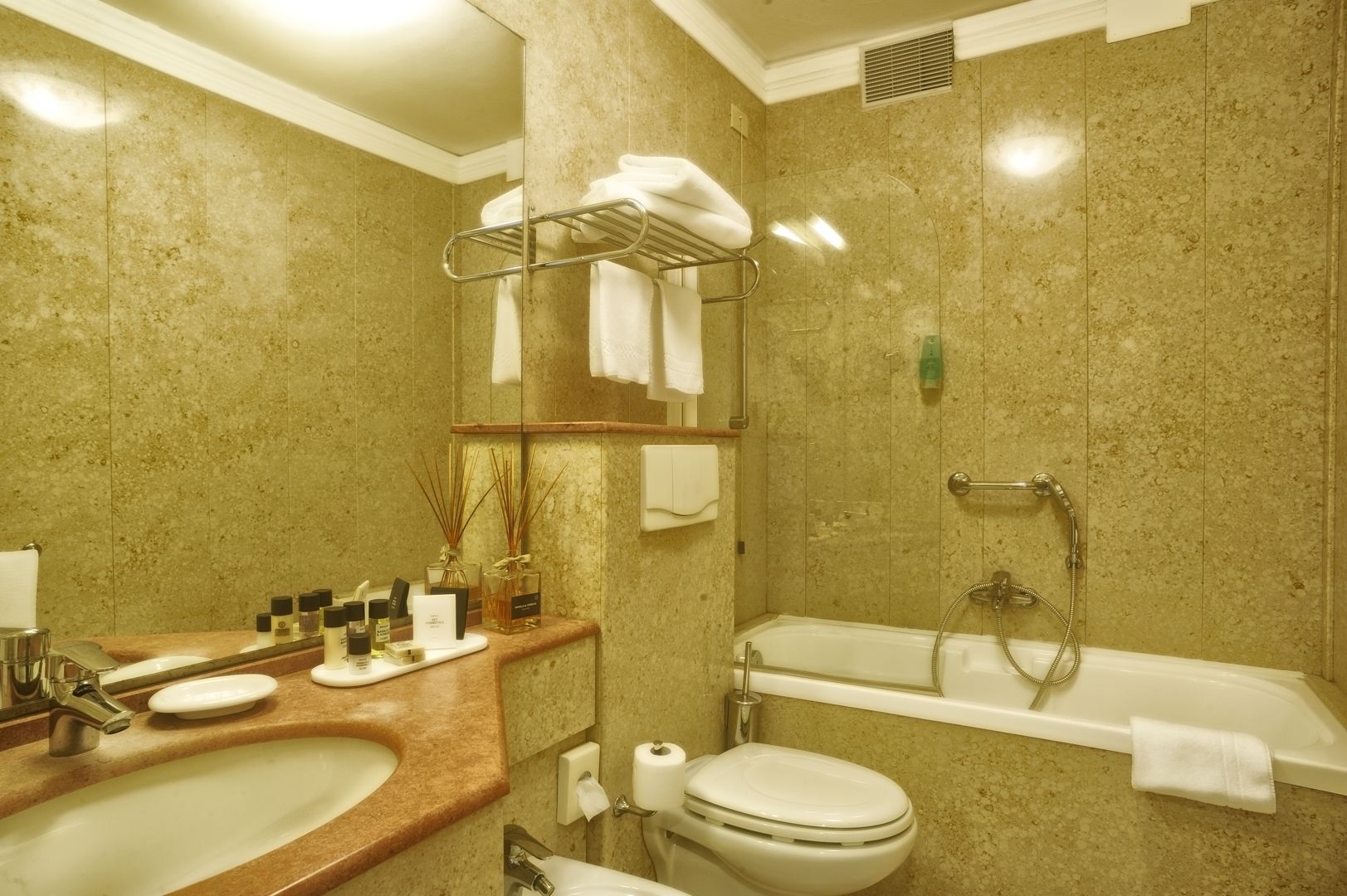 A bathroom with a sink, toilet, and bathtub. There are towels and toiletries on the counter.
