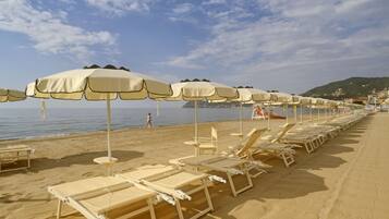 A beach with rows of sun loungers and beach umbrellas.