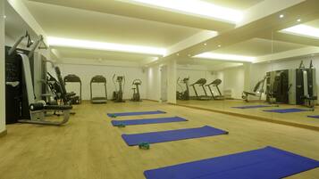 A gym with exercise equipment, blue mats, and mirrors on the walls.