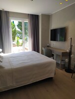 Habitación de hotel con una cama grande, un escritorio, un televisor y vistas a espacios verdes.