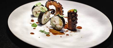 Une assiette de sushis à la pieuvre et au riz, décorée de feuilles vertes.