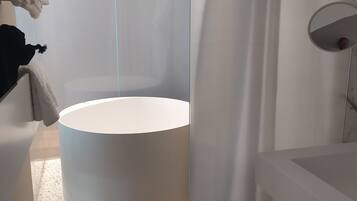 A modern bathroom with a round bathtub, a glass shower enclosure, and a white sink.