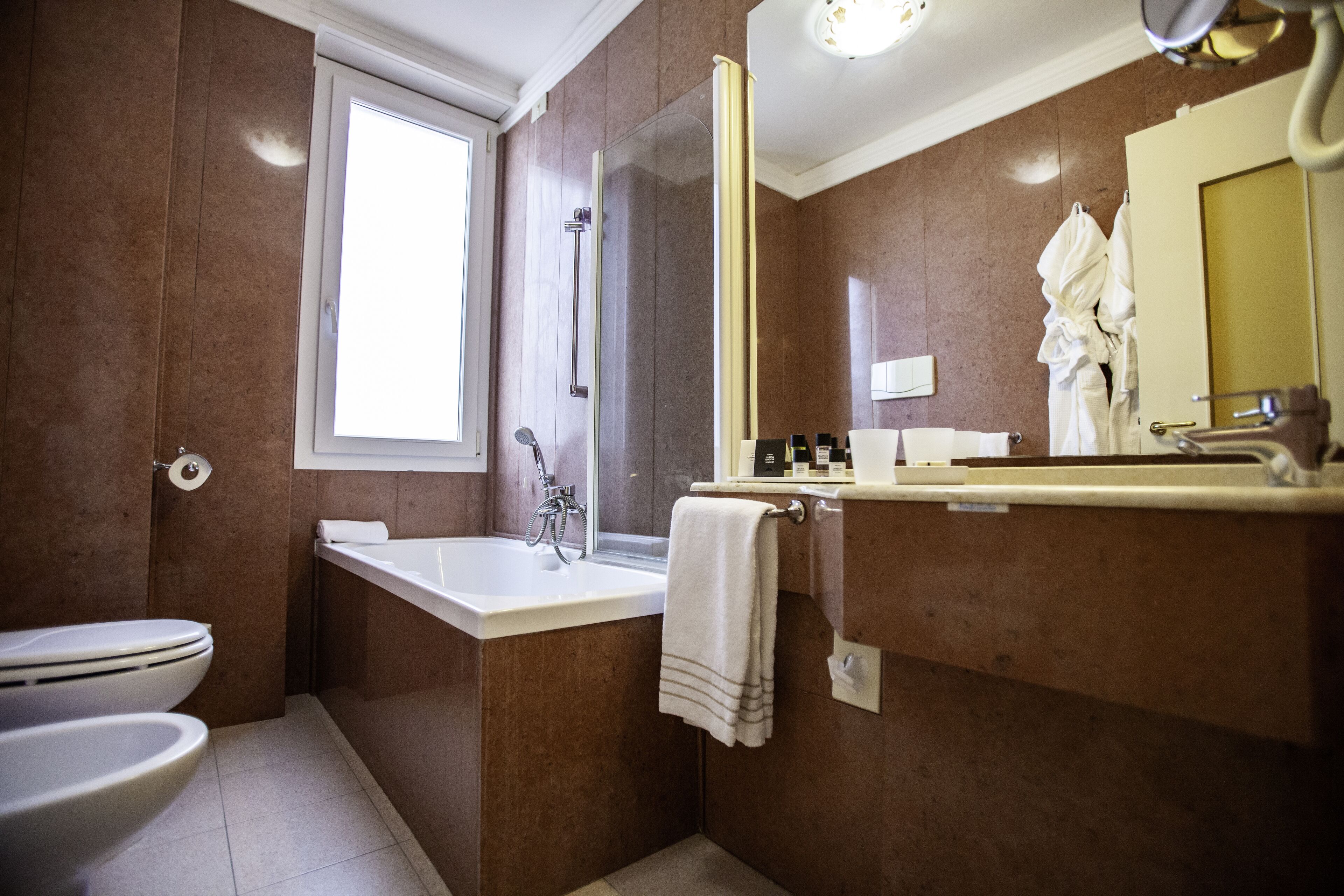 Un baño moderno con bañera, inodoro y un espejo grande.