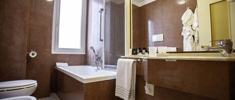 Un baño moderno con bañera, inodoro y un espejo grande.