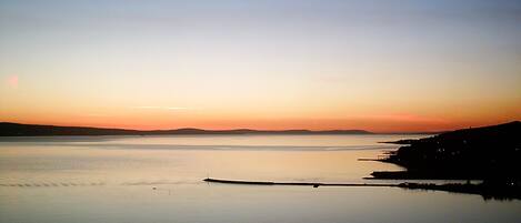 Un lac paisible au coucher du soleil, avec une rive lointaine.