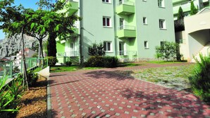 Ein mehrstöckiges Gebäude mit Balkonen, einem gepflasterten Innenhof und umliegender Bepflanzung.