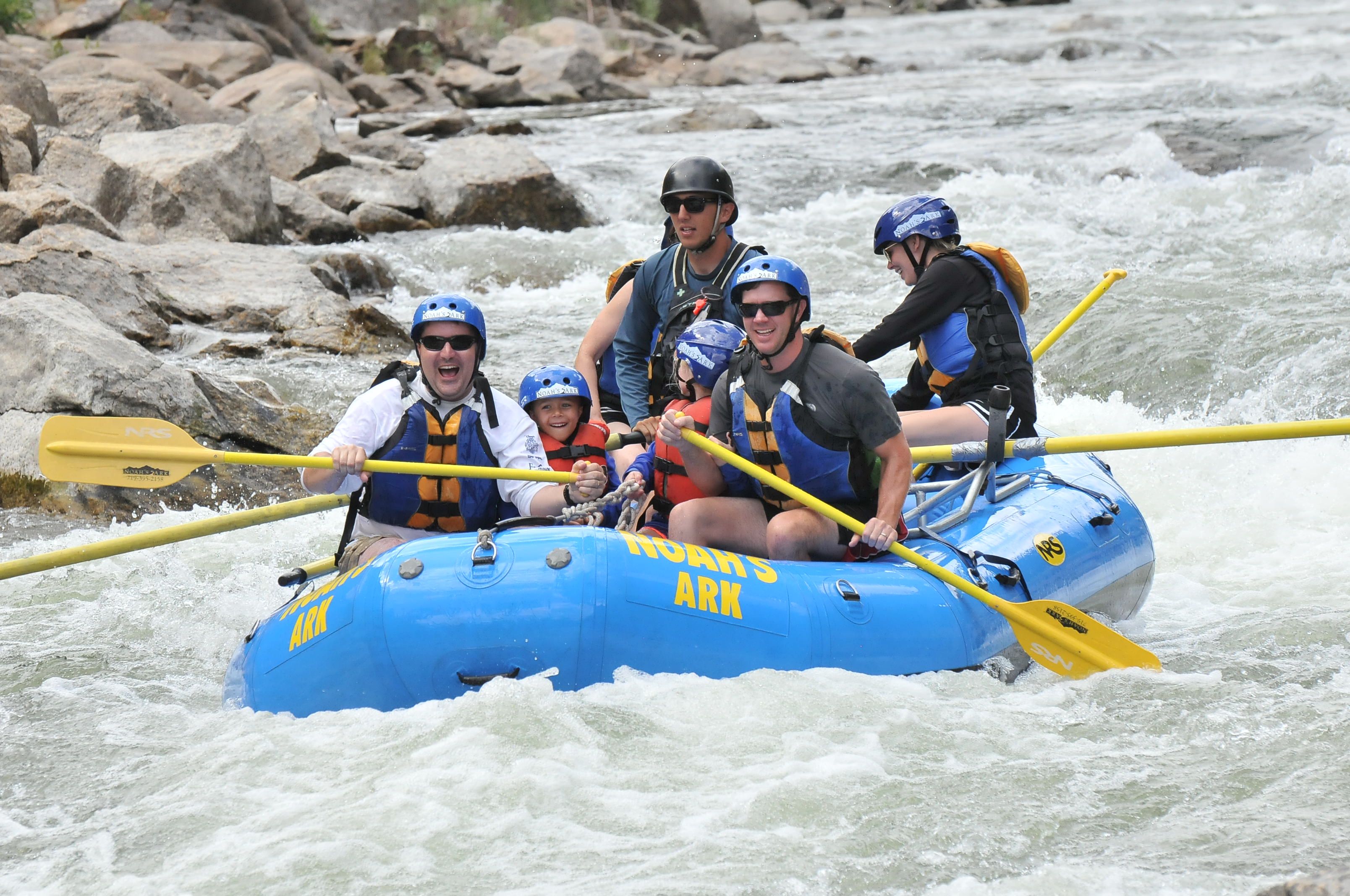 A group of people in a blue raft navigating a river.