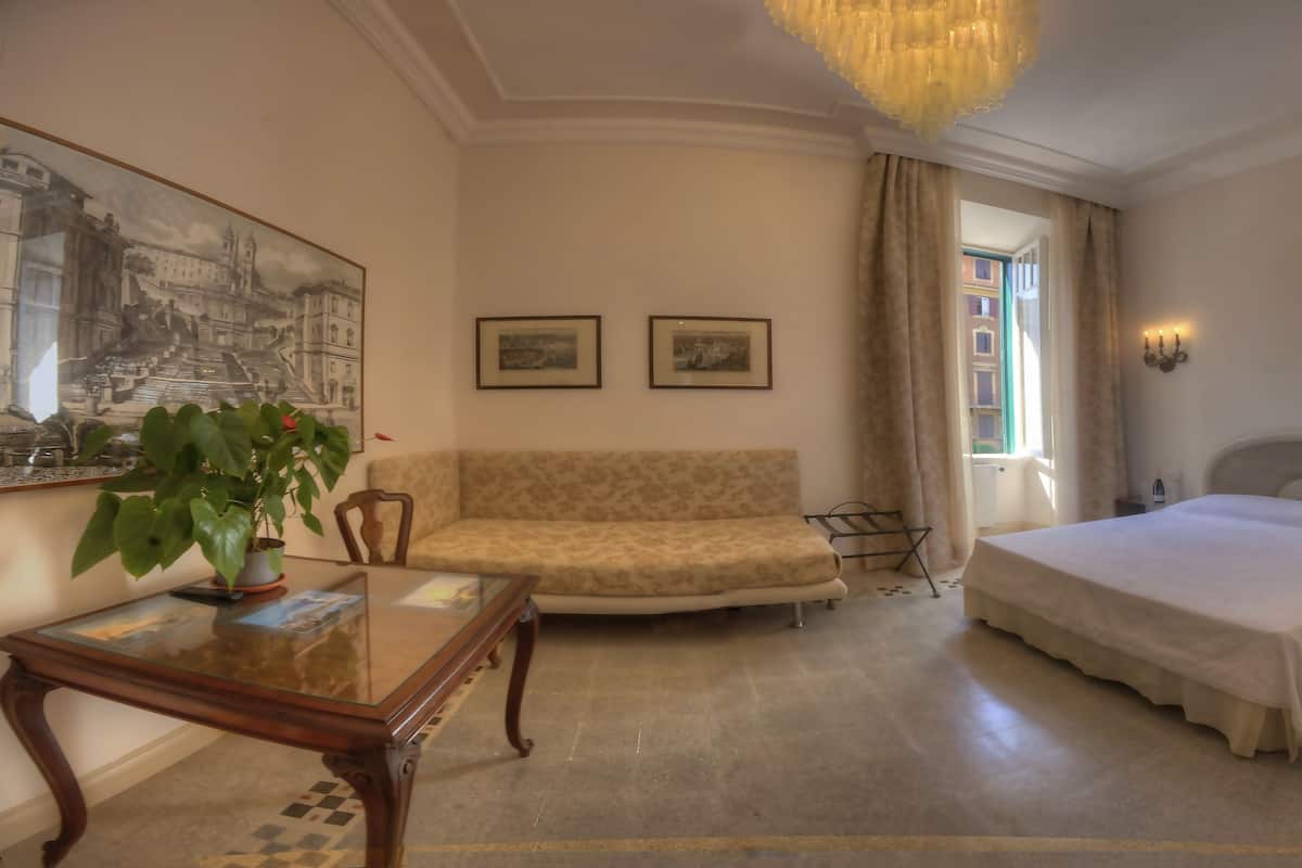 Una habitación de hotel con cama, sofá, mesa de comedor y un amplio ventanal.