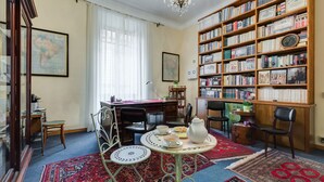 Une bibliothèque chaleureuse avec une grande étagère, une table à manger avec des chaises et une carte accrochée au mur.