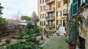 Une cour intérieure agrémentée de plantes en pot et un bâtiment doté de balcons.
