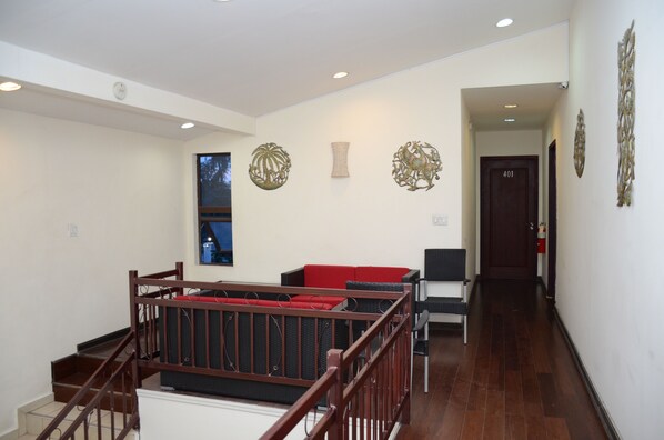 A spacious hallway with a staircase leading to a balcony, a red cushioned seating area, and a door marked 401. - Elite Hotel (Port-au-Prince)