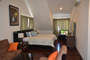 A hotel room with a bed, a sofa, a desk, and a TV.