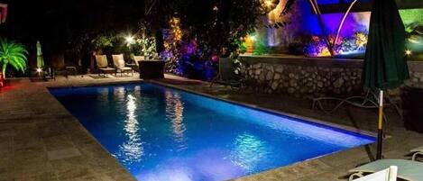 A swimming pool with a stone wall and a waterfall feature.