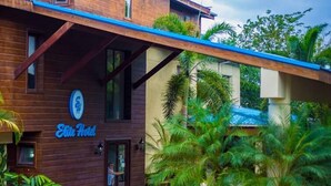 A two-story building with a wooden facade and a blue roof. The sign "Elite Hotel" is visible on the front. - Elite Hotel (Port-au-Prince)