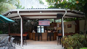 An outdoor bar area with a date sign, seating, and a counter. - Elite Hotel (Port-au-Prince)