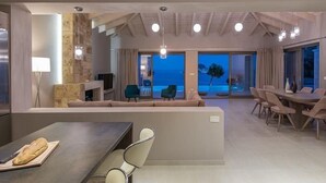 A modern interior with a dining area, a sofa, and a view of the ocean. - Avra Luxury Villa (Zakynthos)