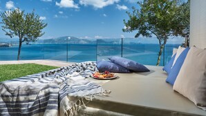 A balcony with a view of the sea, a sofa with cushions, and a plate of fruit. - Avra Luxury Villa (Zakynthos)