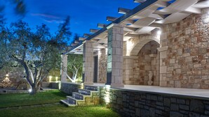 A modern outdoor patio area with stone walls and a pergola structure. - Avra Luxury Villa (Zakynthos)