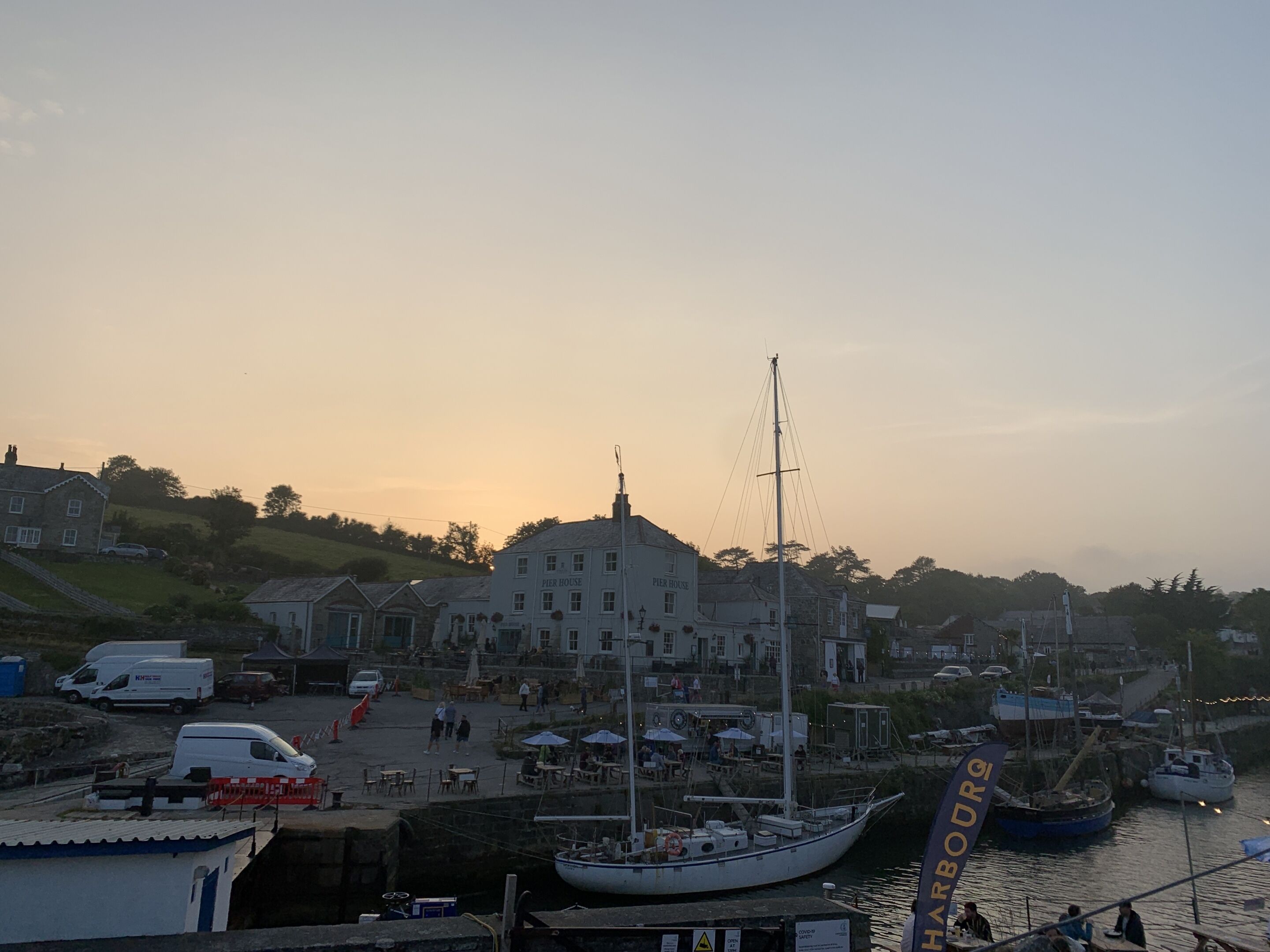 Ein Hafen mit einer Pier, Booten und einem Café am Wasser.