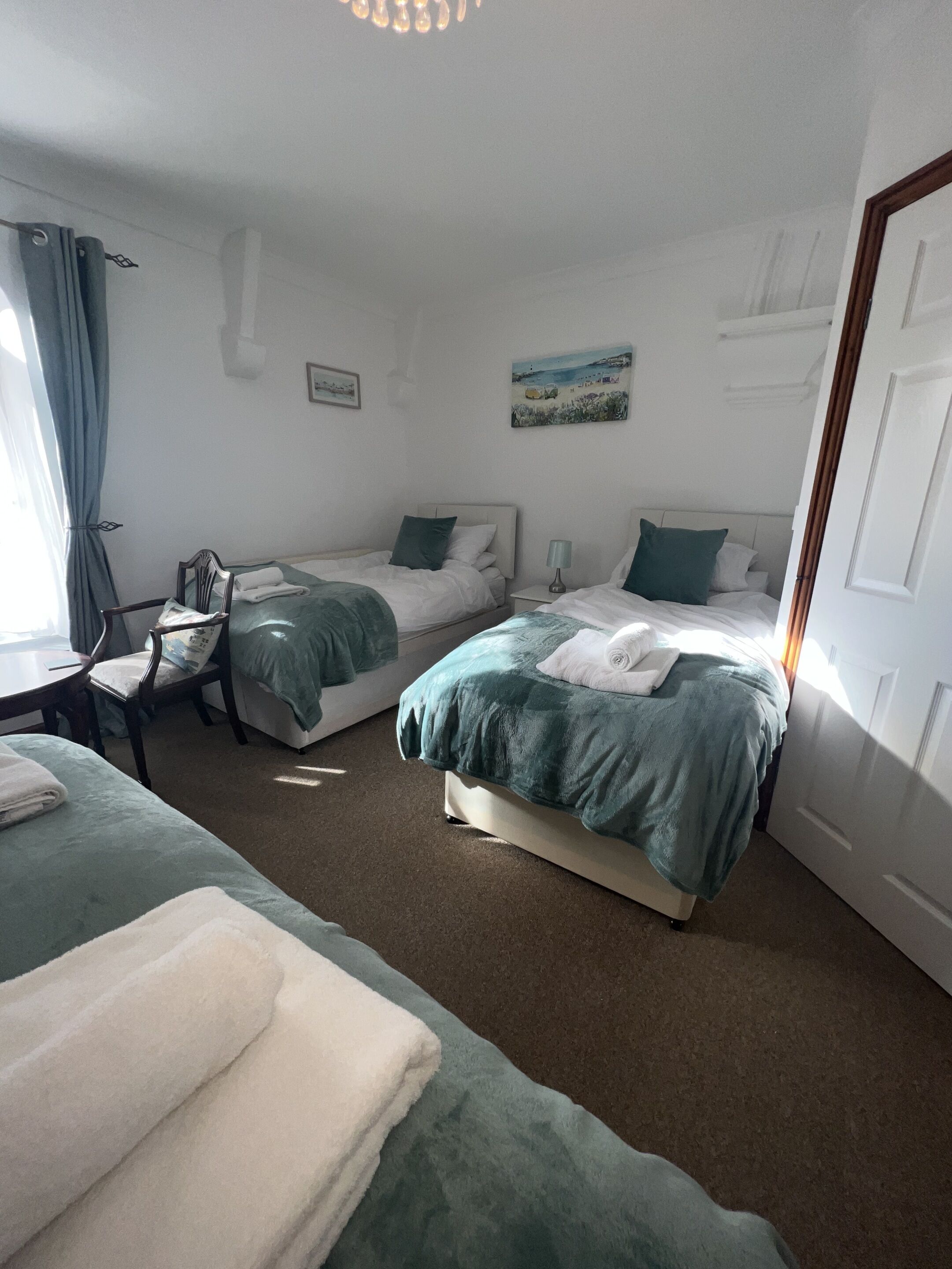 Una habitación de hotel con dos camas, una silla, un escritorio y un cuadro en la pared.