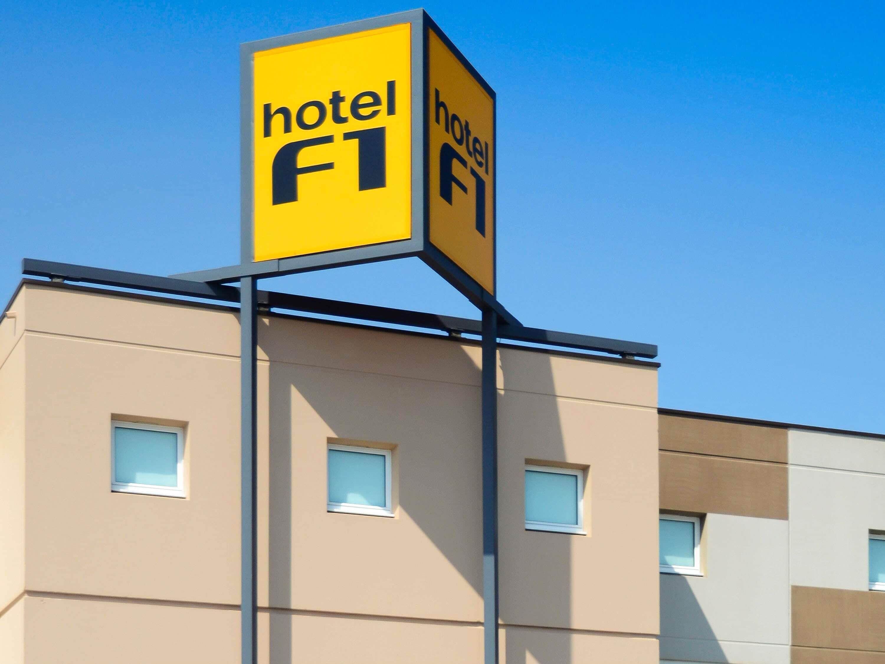 A hotel sign with the name 'hotel F1' on a modern building with multiple windows.