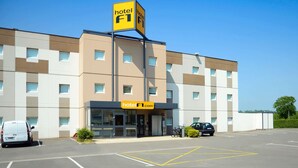 A hotel building with a prominent 'hotel F1' sign, a parking lot, and a few parked cars. - hotelF1 Avranches Baie du Mont Saint Michel (Saint-Quentin-sur-le-Homme)