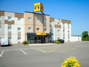 A hotel building with a prominent 'hotel F1' sign, a parking lot, and a few parked cars. - hotelF1 Avranches Baie du Mont Saint Michel (Saint-Quentin-sur-le-Homme)