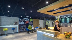 Een moderne lounge met een receptiebalie, zitplaatsen en een muurschildering van boeken en een wereldbol.