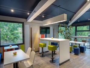 Un intérieur moderne avec un bar, des espaces pour s’asseoir et de grandes fenêtres.