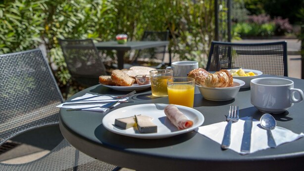Een ronde tafel met ontbijtproducten, waaronder croissants, sinaasappelsap en een bord met een rolletje gebak.