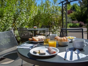 A round table with breakfast items including croissants, orange juice, and a plate with a rolled pastry. - ibis budget Brignoles Provence Verte (Brignoles)