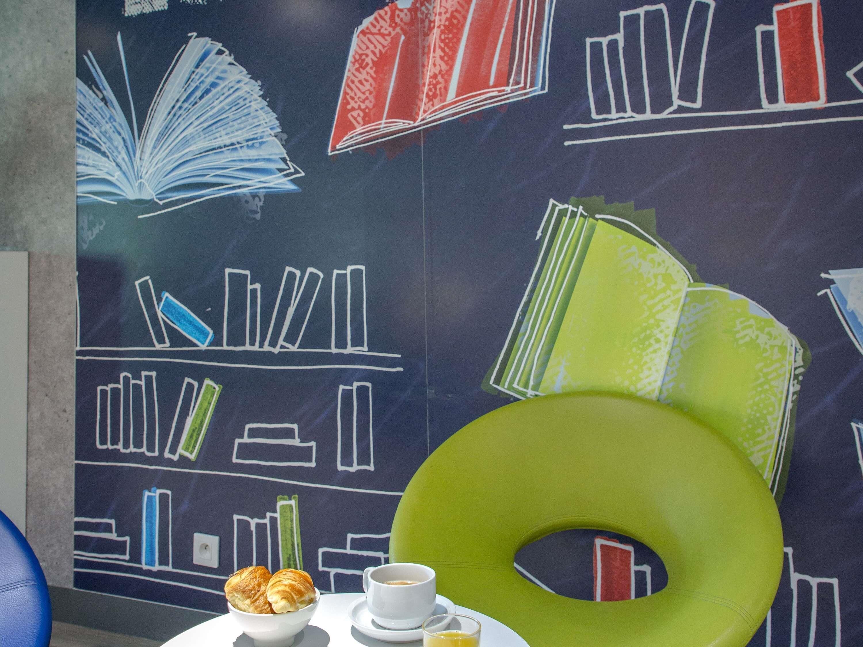 Una mesa con un croissant, una taza de café y un donut verde.