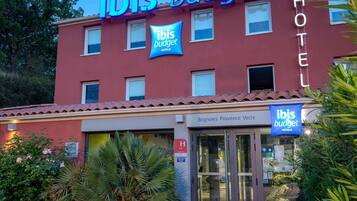 A hotel with 'ibis budget' signage, a glass entrance, and a red facade.