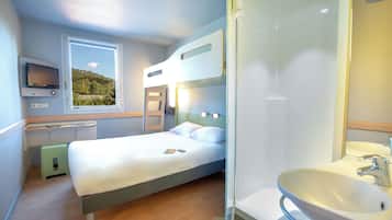 Hotelkamer met een bed, nachtkastje, televisie, raam met uitzicht en een badkamer met wastafel en spiegel.