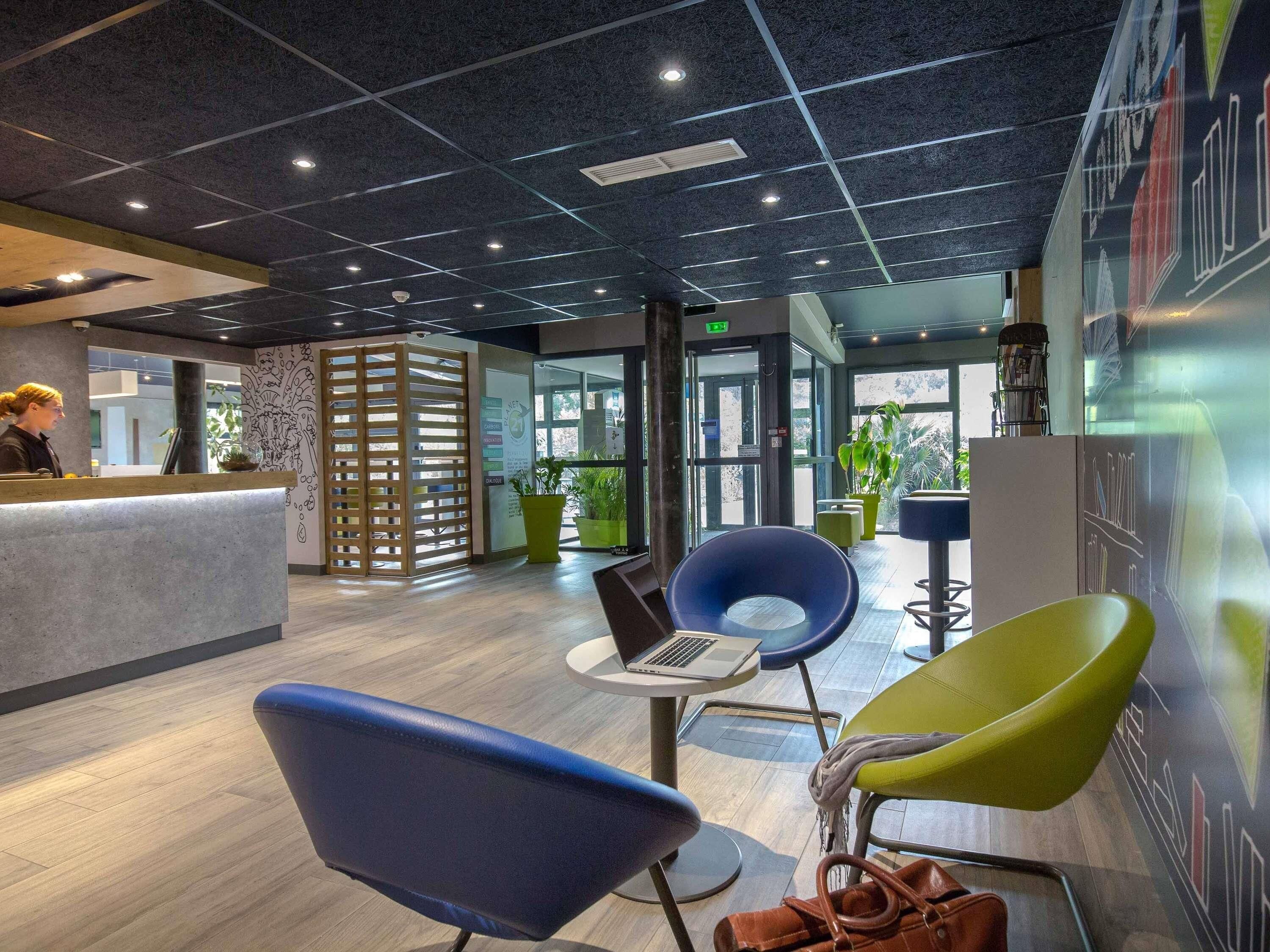 A modern reception area with a counter, seating, and a view of the outdoors.