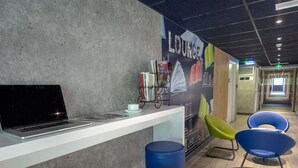 Een zithoek met een laptop op een aanrecht, een boekenkast en kleurrijke stoelen.