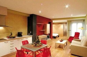 Un espacio habitable compacto con kitchenette, comedor y sofá.