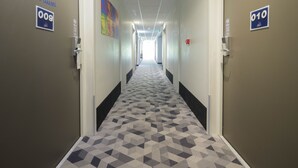 A hallway with patterned carpet, doors numbered 009 and 010, and a colorful artwork on the wall.