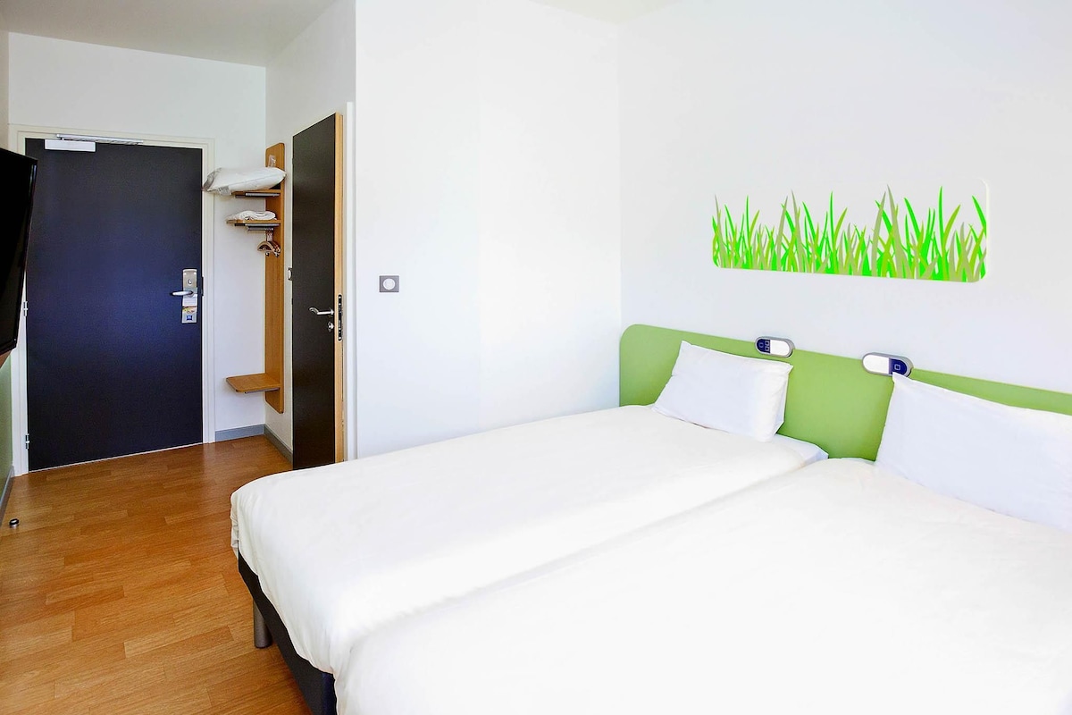 A hotel room with a bed, a wardrobe, and a door.