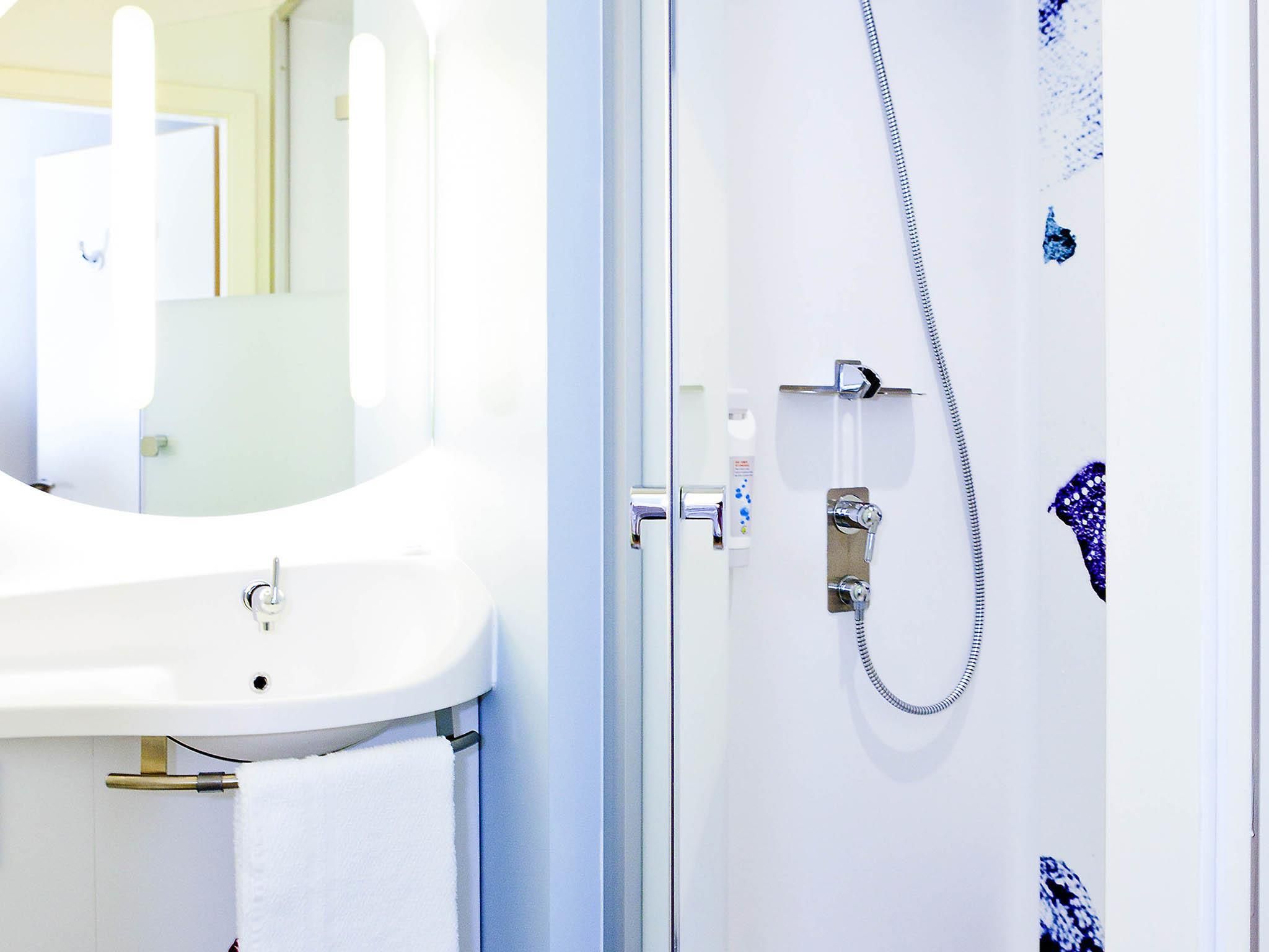 A bathroom with a sink, mirror, and shower.